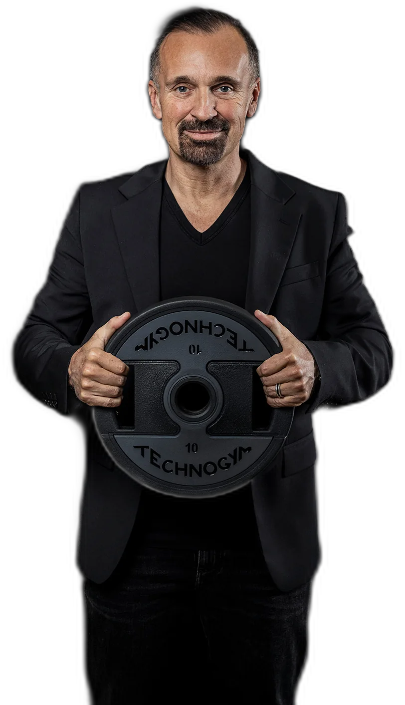 Gottfried Wurpes hält eine Technogym Hantelscheibe